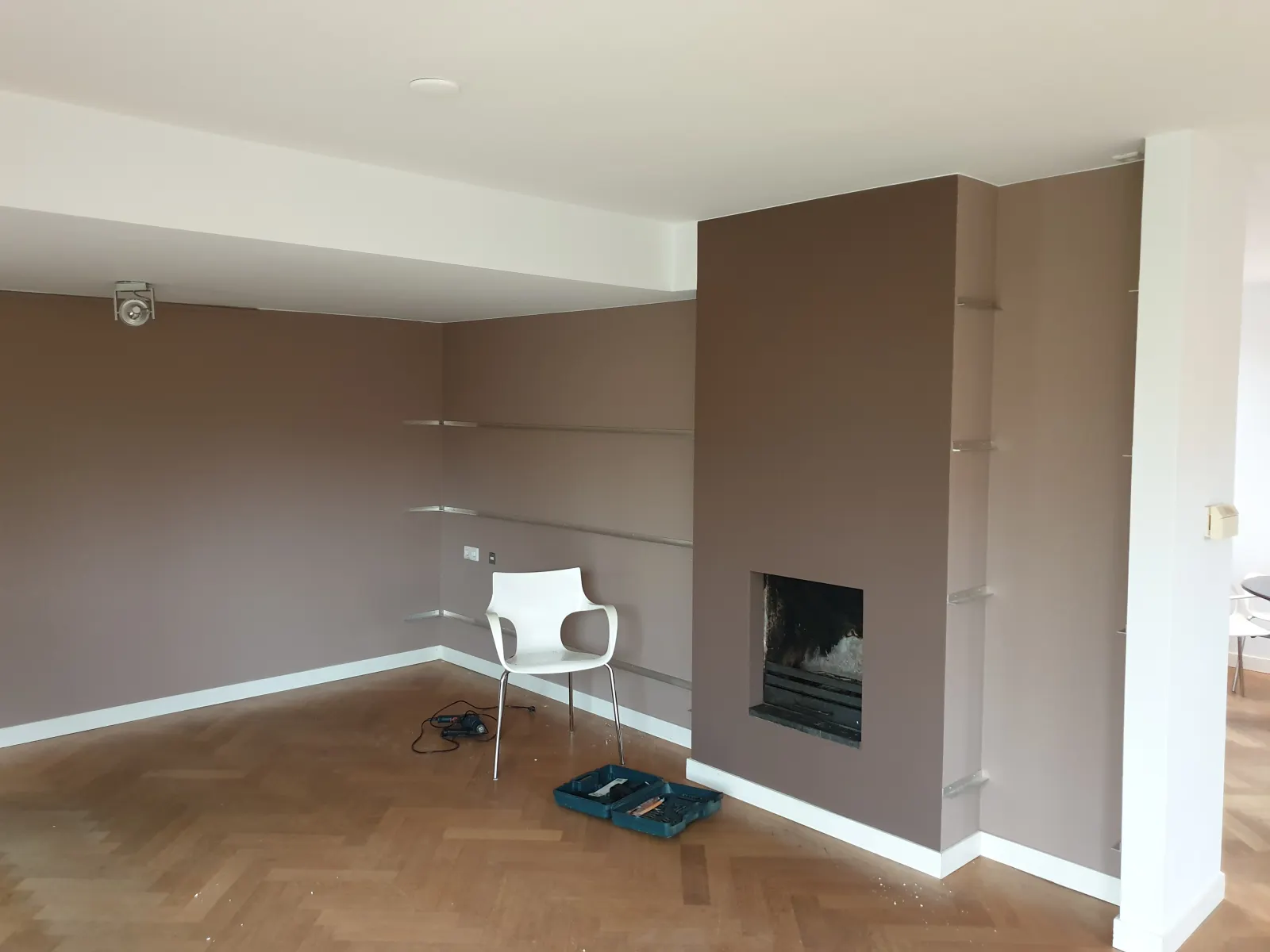 Binnenschilderwerk — strakke woonkamer met warme kleur en haardwand